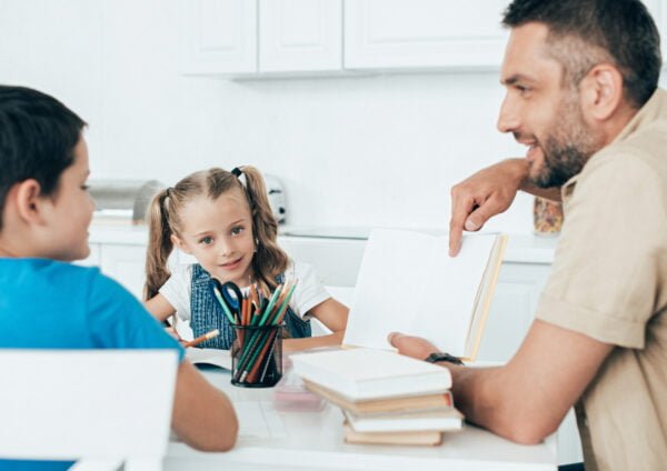 smiling father and kids doing homework together at home