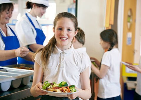 Elev med en tallrik mat i skolmatsalen